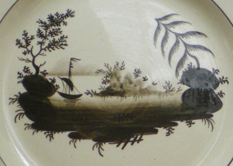 Assiette décorée d'un paysage de style chinois en camaïeu brun.